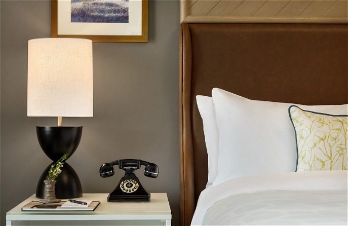 Hotel bed with table with lamp and phone