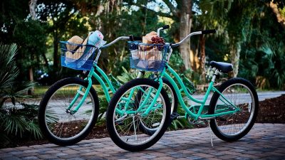 Two turquoise bicycles with baskets filled with picnic related items